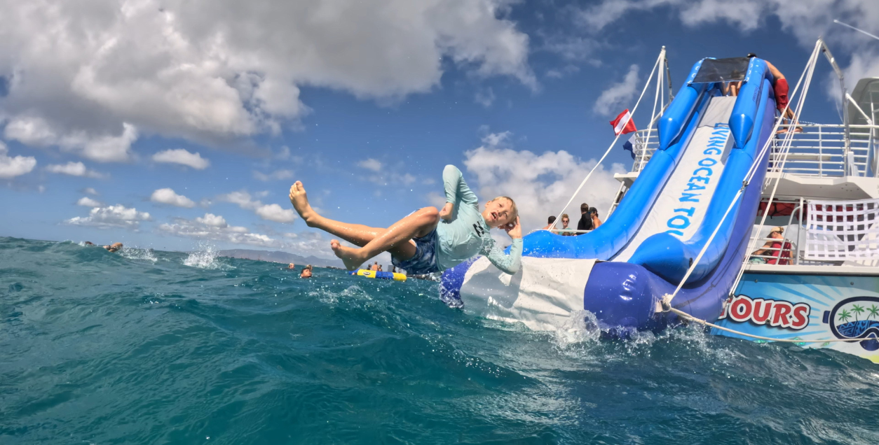 boy sliding off waterslide on boat tour in ohau