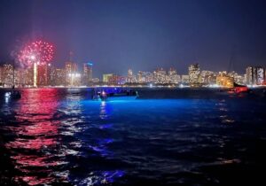 Boat on the water during a Waikiki Fireworks Cruise with red fireworks in the sky