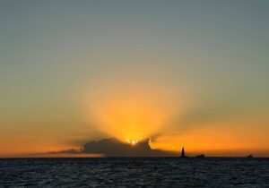 a sailboat on the horizon at sunset in Waikiki seen during a boat tour